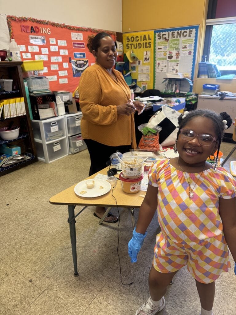 Adult and child smiling in a classroom.