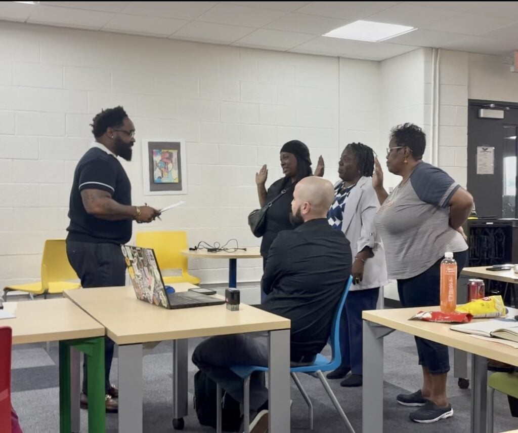 Adults standing with hands raised during a group activity.
