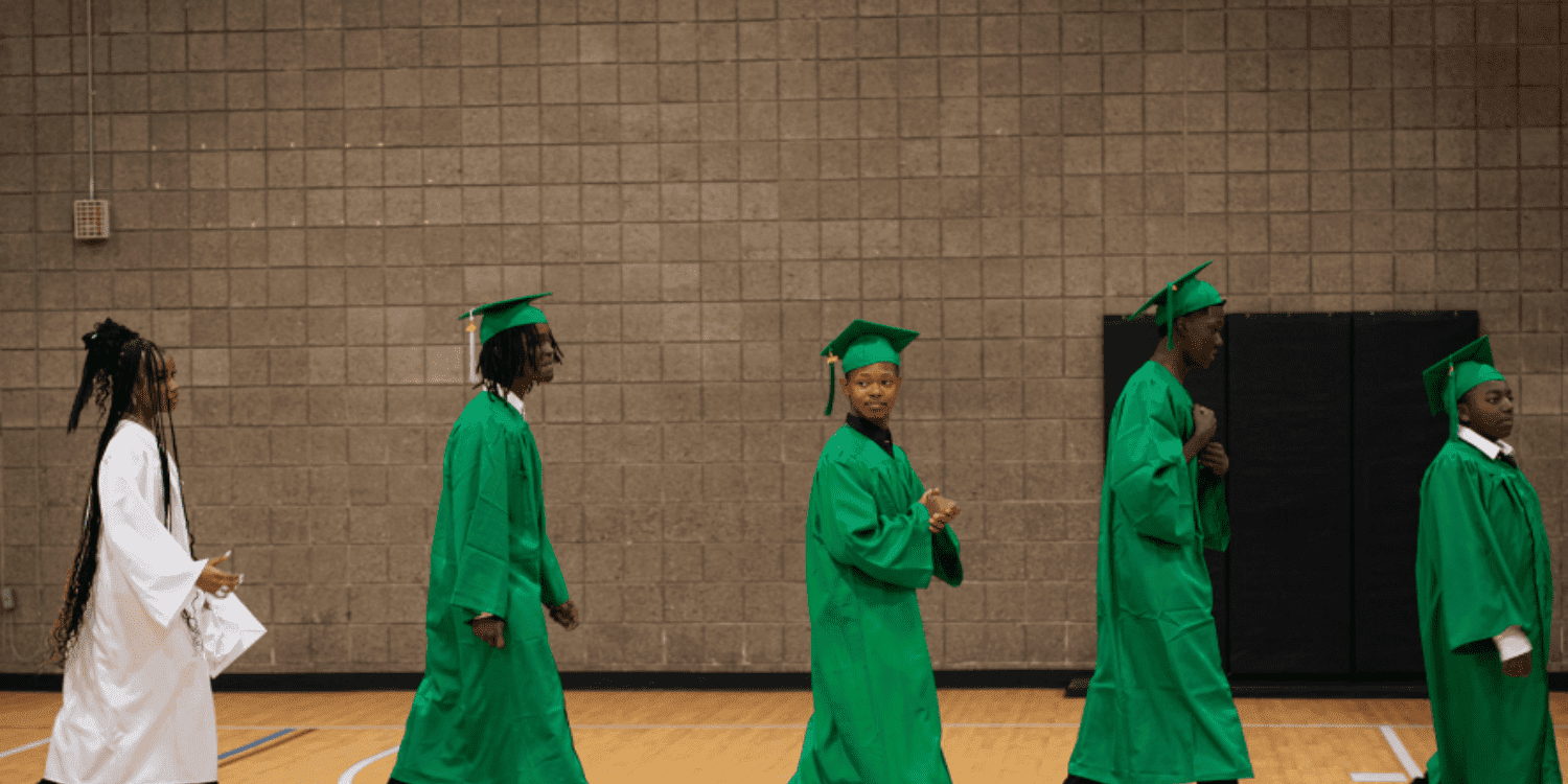 Children in graduation gowns walking in a line.