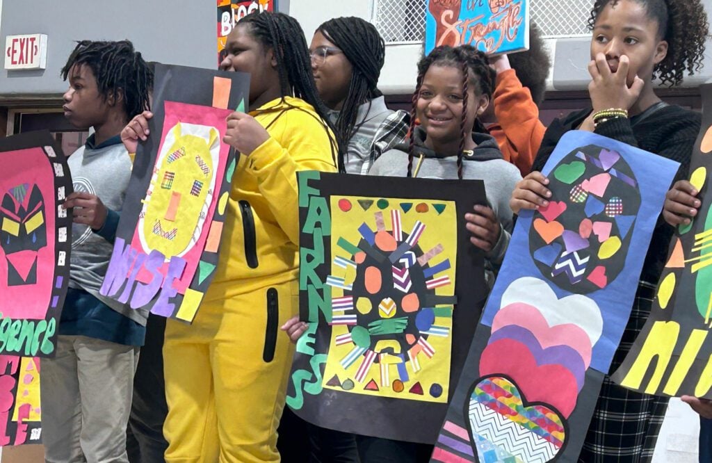 Children display colorful artwork with shapes and designs.