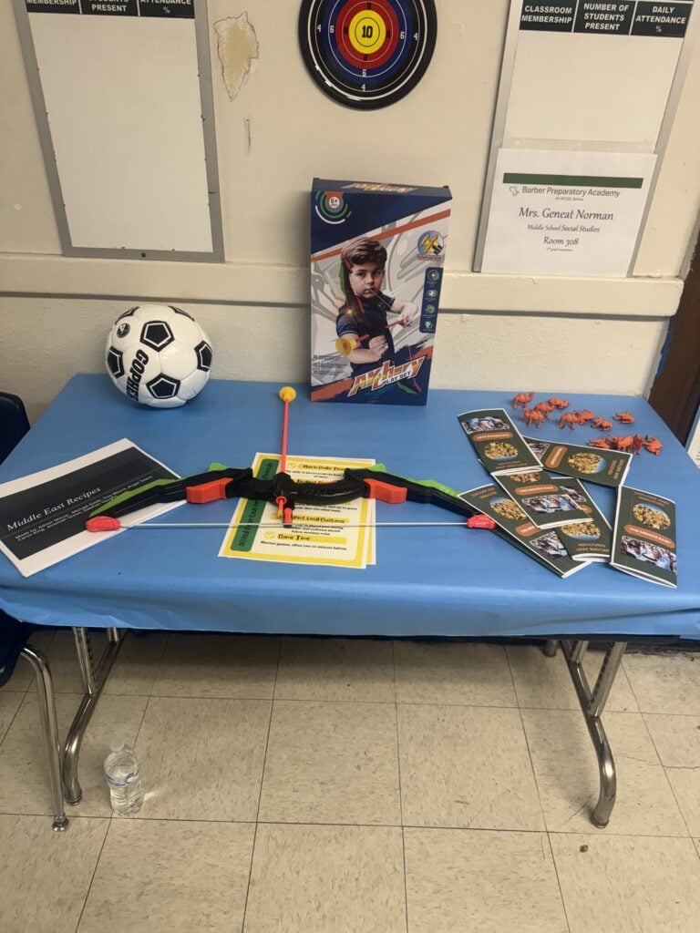 Table with soccer ball, archery set, recipe booklets, and animal figurines.