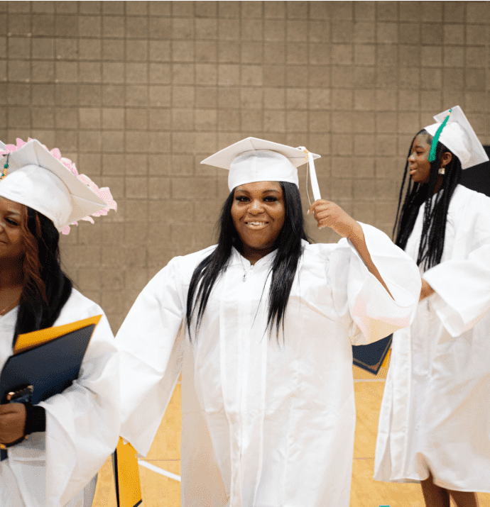 Three adults in white graduation caps and gowns.