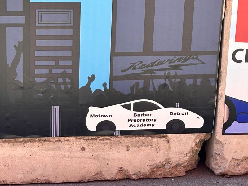 Mural section with white race car, city buildings, and silhouetted crowd.