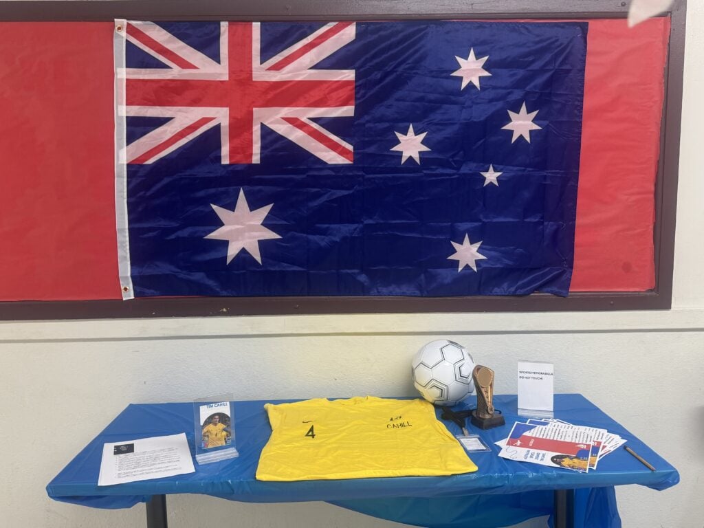 Display with yellow jersey, soccer ball, trophy, and Australian flag.