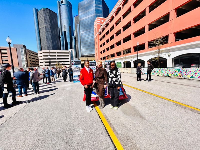 Three adults stand on a street in a city.