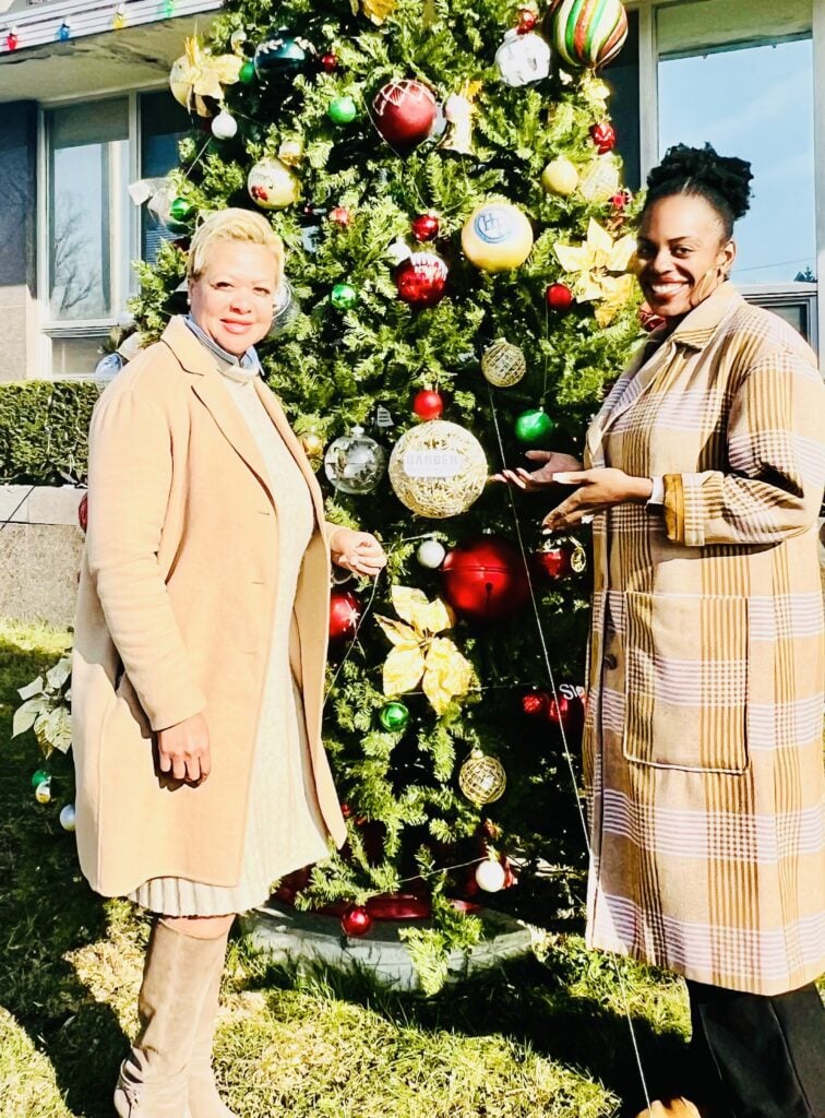Two adults smiling next to a decorated Christmas tree.
